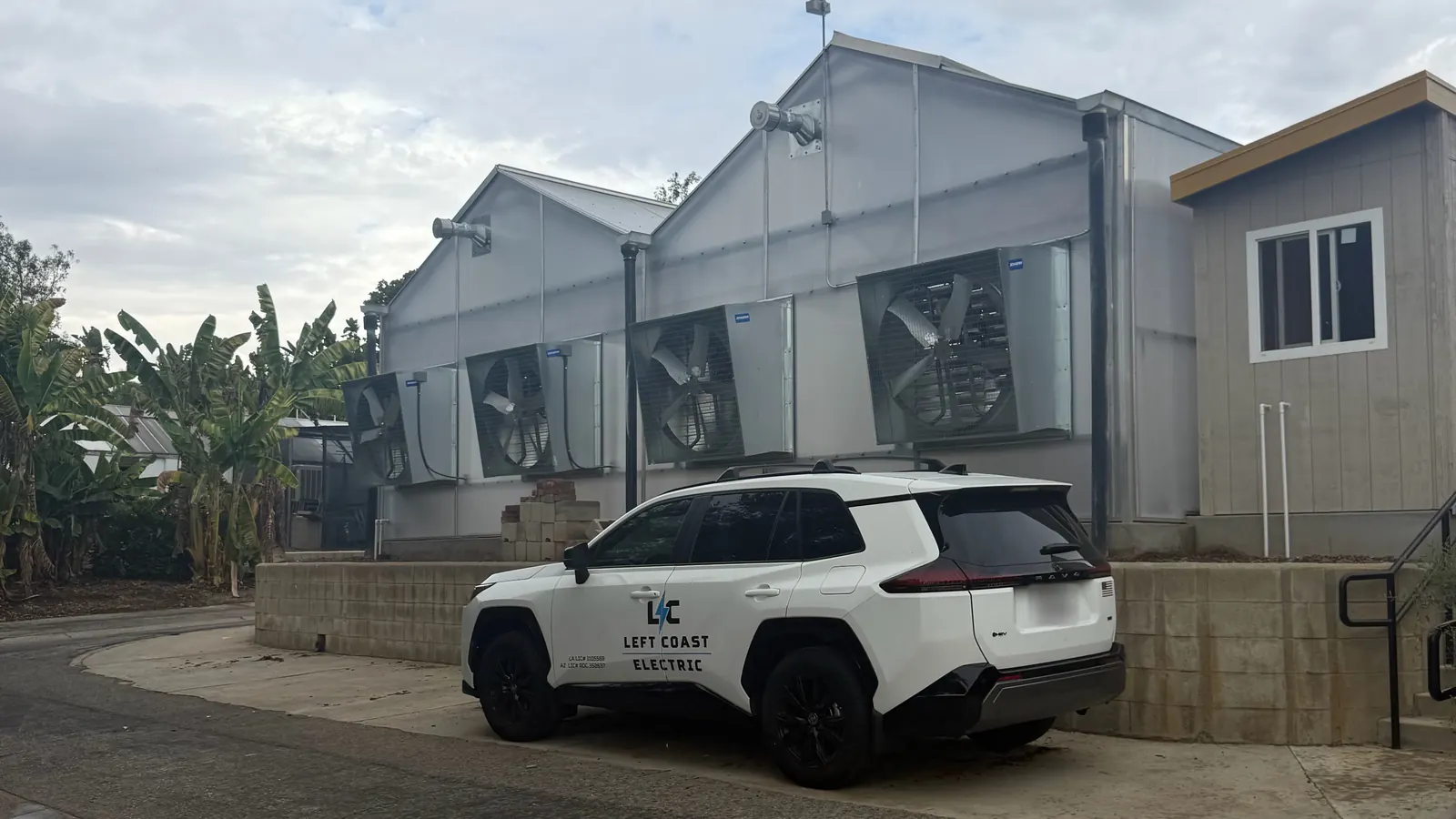 Left Coast Electric vehicle parked outside a greenhouse with large wall-mounted exhaust fans at the LA County Arboretum in Arcadia, CA