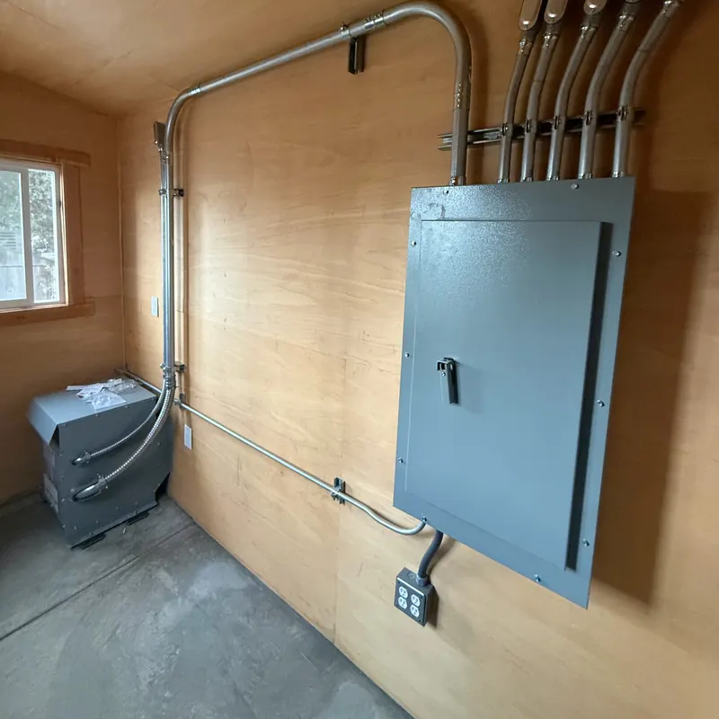 Panelboard with conduit runs and a transformer in an electrical room at the LA County Arboretum greenhouses