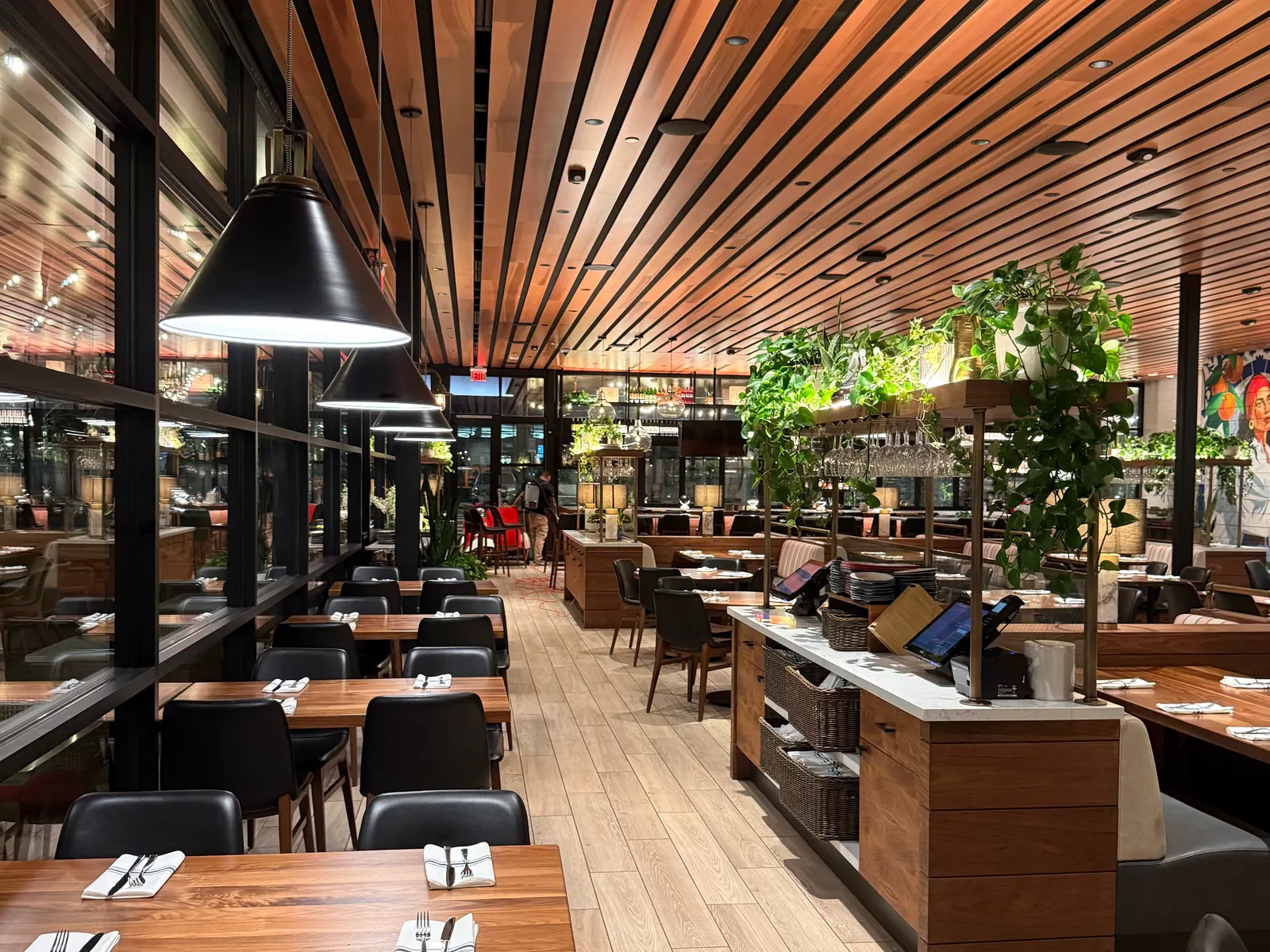 North Italia Brea dining room with black pendant lights and a wood-slat ceiling