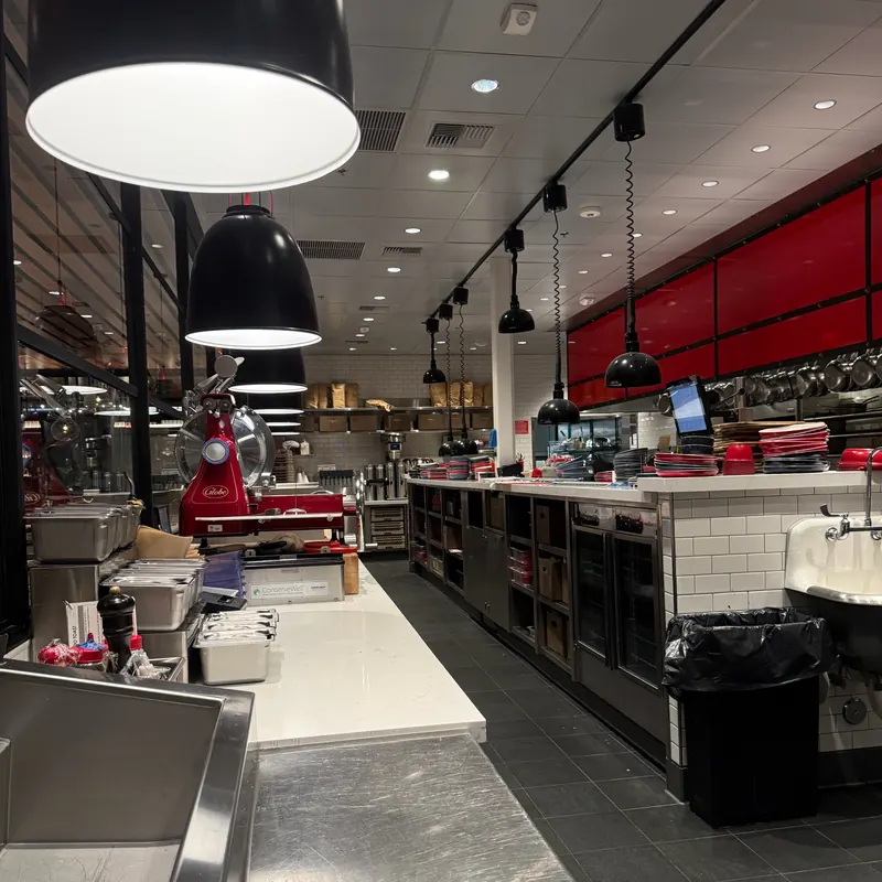 Kitchen line with black pendants and track lighting at North Italia Brea